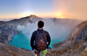 man looking down at the mammoth kawah ijen crater lake